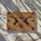 Rectangular coir doormat with two standing stags, triple moon symbol, and tree of life design in black on natural tan background.